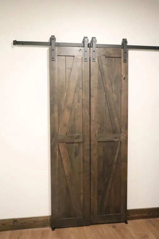Sliding barn door in stained hardwood on black track hardware — built by Amish Heritage Woodworks, Wisconsin
