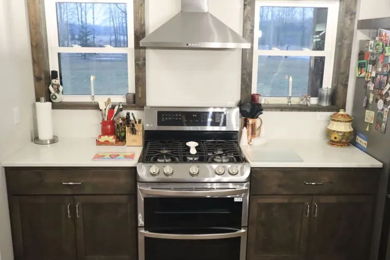 Stained alder base cabinets flanking a gas range — built by Amish Heritage Woodworks, Wisconsin