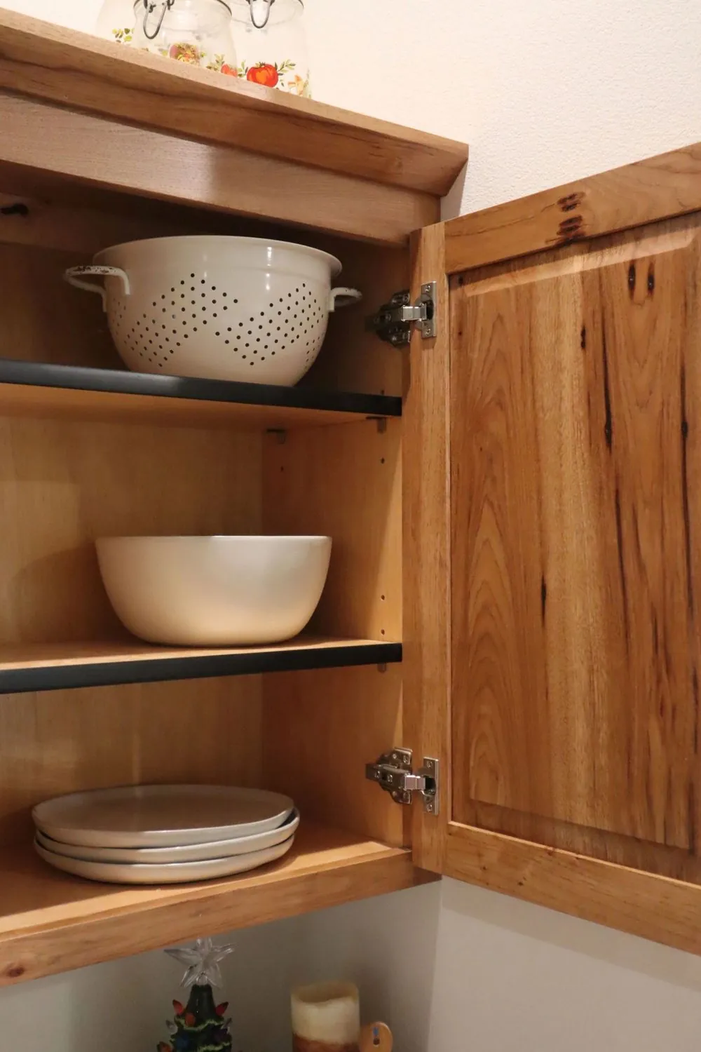 Open cabinet door showing solid wood construction and adjustable shelving inside a hickory cabinet