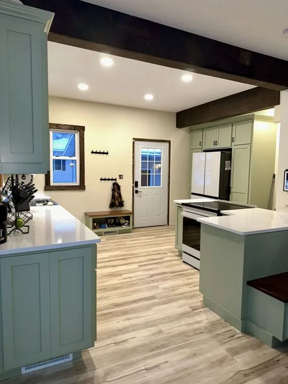 Sage green painted maple kitchen with quartz counters and a built-in banquette